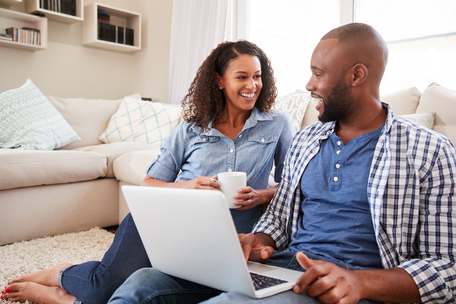 Couple budgetting together on laptop while drinking coffee smiling